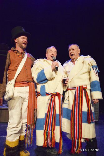 Daniel Leclair, le président du Festival du Voyageur, chante l’air traditionnel Prendre un p’tit coup avec les récipiendaire du capot honorifique, Gérard Curé (au centre) et Paul Desrosiers (à droite).