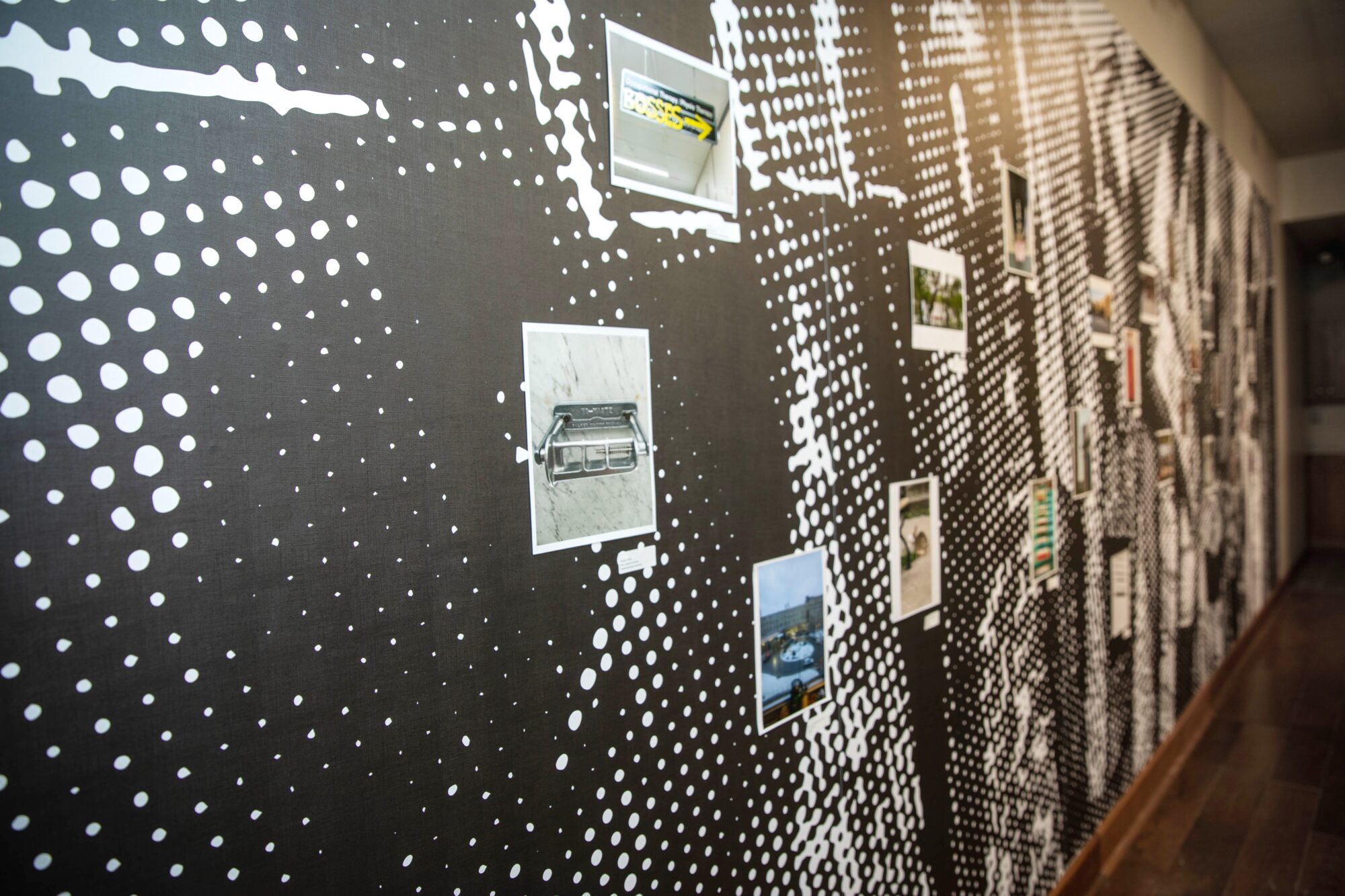 Mur noir et blanc avec des photos qui présentent la nouvelle exposition de la Galerie Buhler