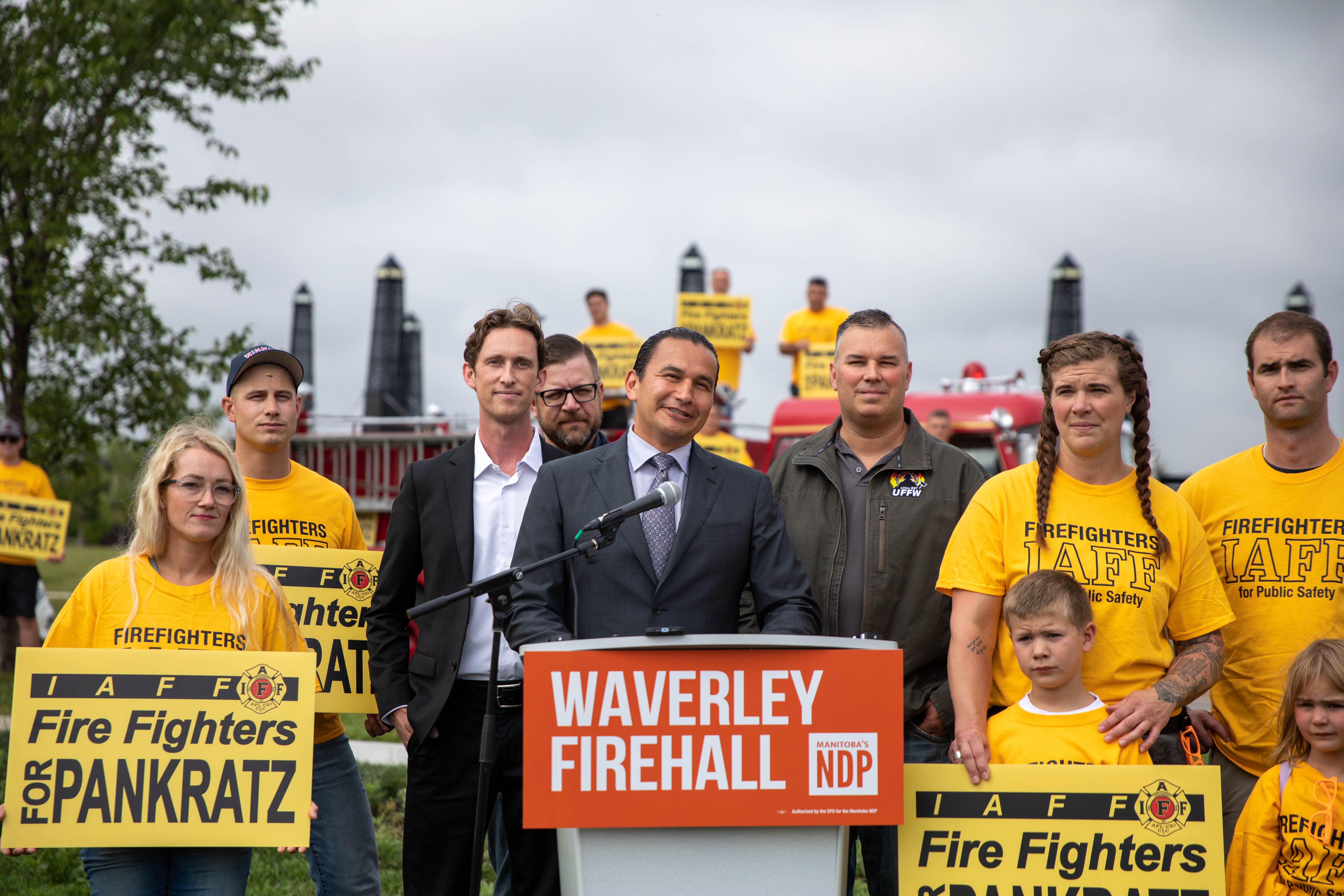 Devant le Podium, Wab Kinew, chef du NPD. Immédiatement à droite Tom Bilous Président des United Fire Fighters of Winnipeg. Immédiatement à gauche de Wab Kinew David Pankratz le candidat du NPD pour la circonscription Waverley West. Tous entourés par des pompiers et leurs familles. (Photo : Raphaël Boutroy)