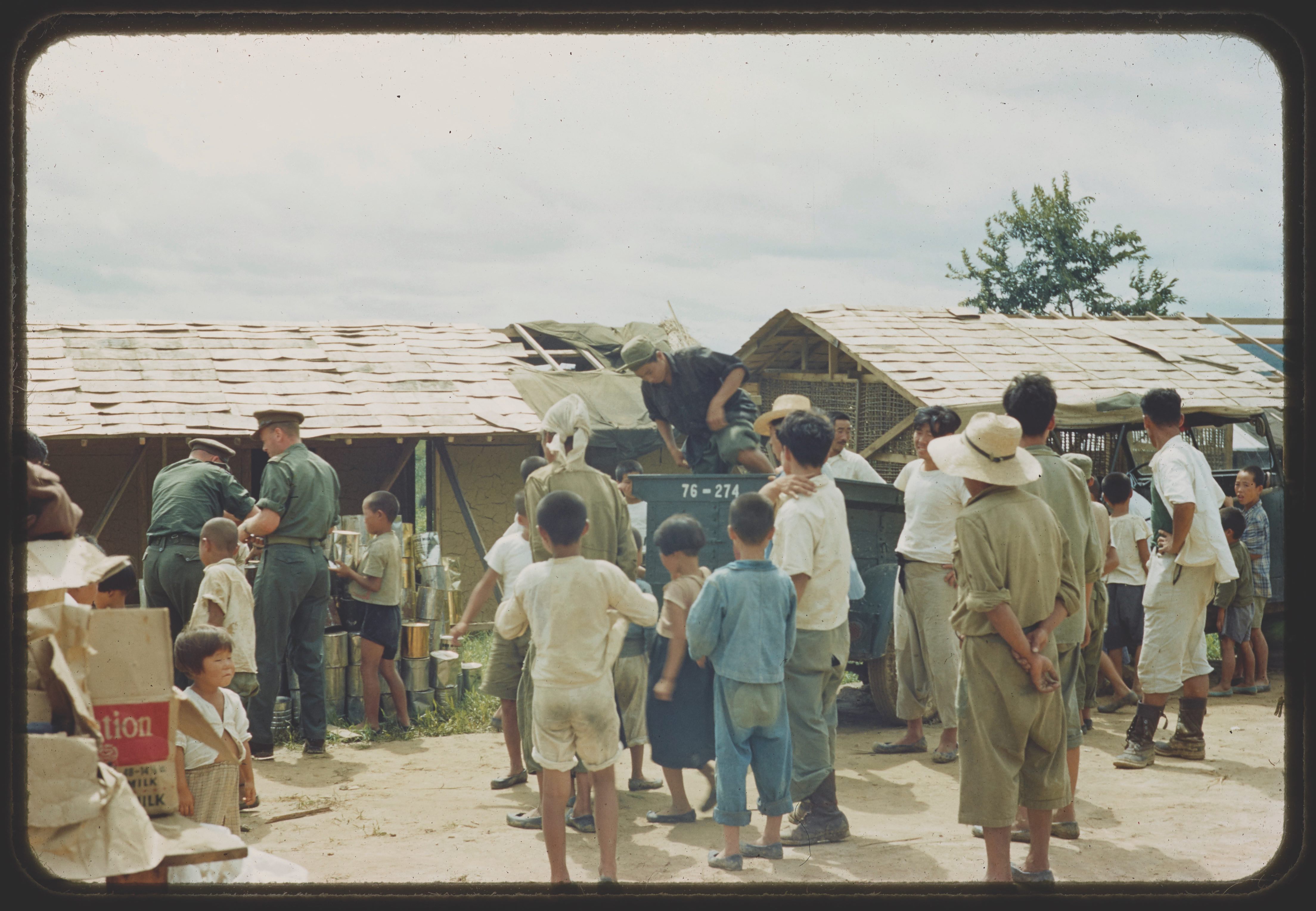 Des soldats canadiens distribuant de la nourriture à la population locale pendant la guerre. 
