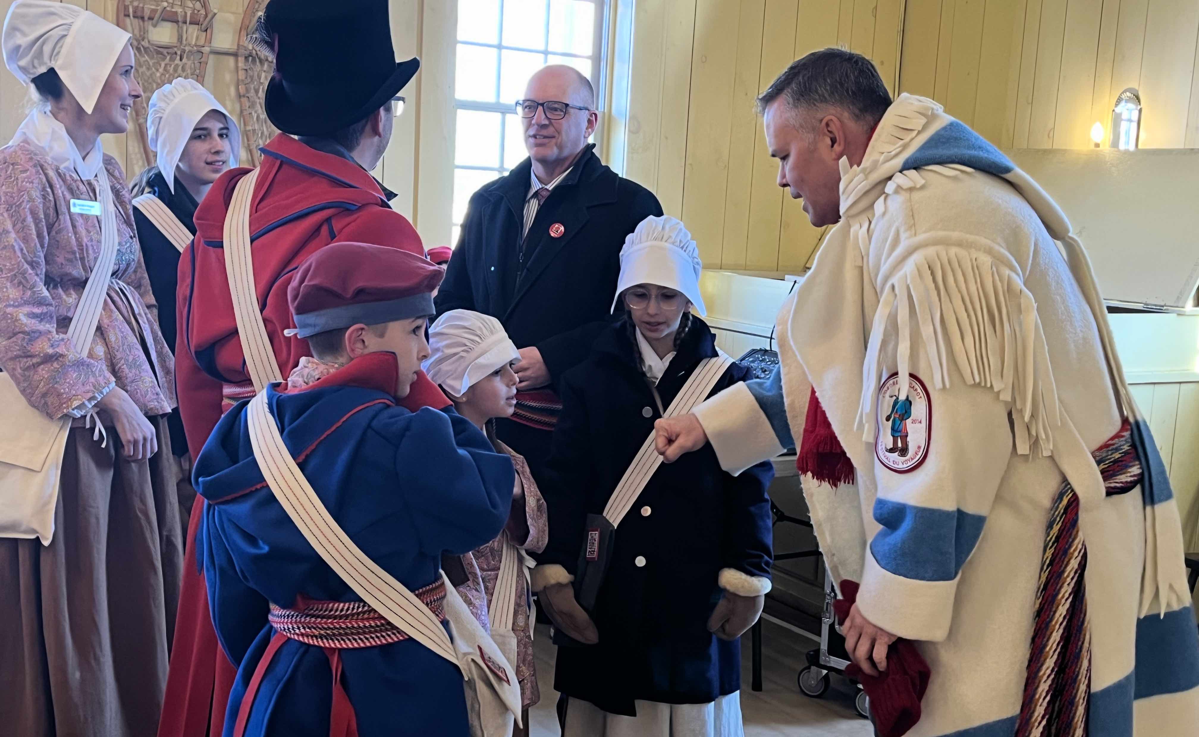 À la veille du lancement du Festival du Voyageur 2024, tandis qu’à l’arrière-plan, les nouveaux Voyageurs officiels Danièle et Philippe Hutlet, ainsi que leur fille aînée Danika, discutent avec le maire de Winnipeg, Scott Gillingham, le député de Saint-Boniface Robert Loiselle (à l’avant), qui a lui-même été enfant de Voyageurs officiels quand il avait une dizaine d’années, partage avec Rémi, Mia et Élise Hutlet ses souvenirs et conseils.
