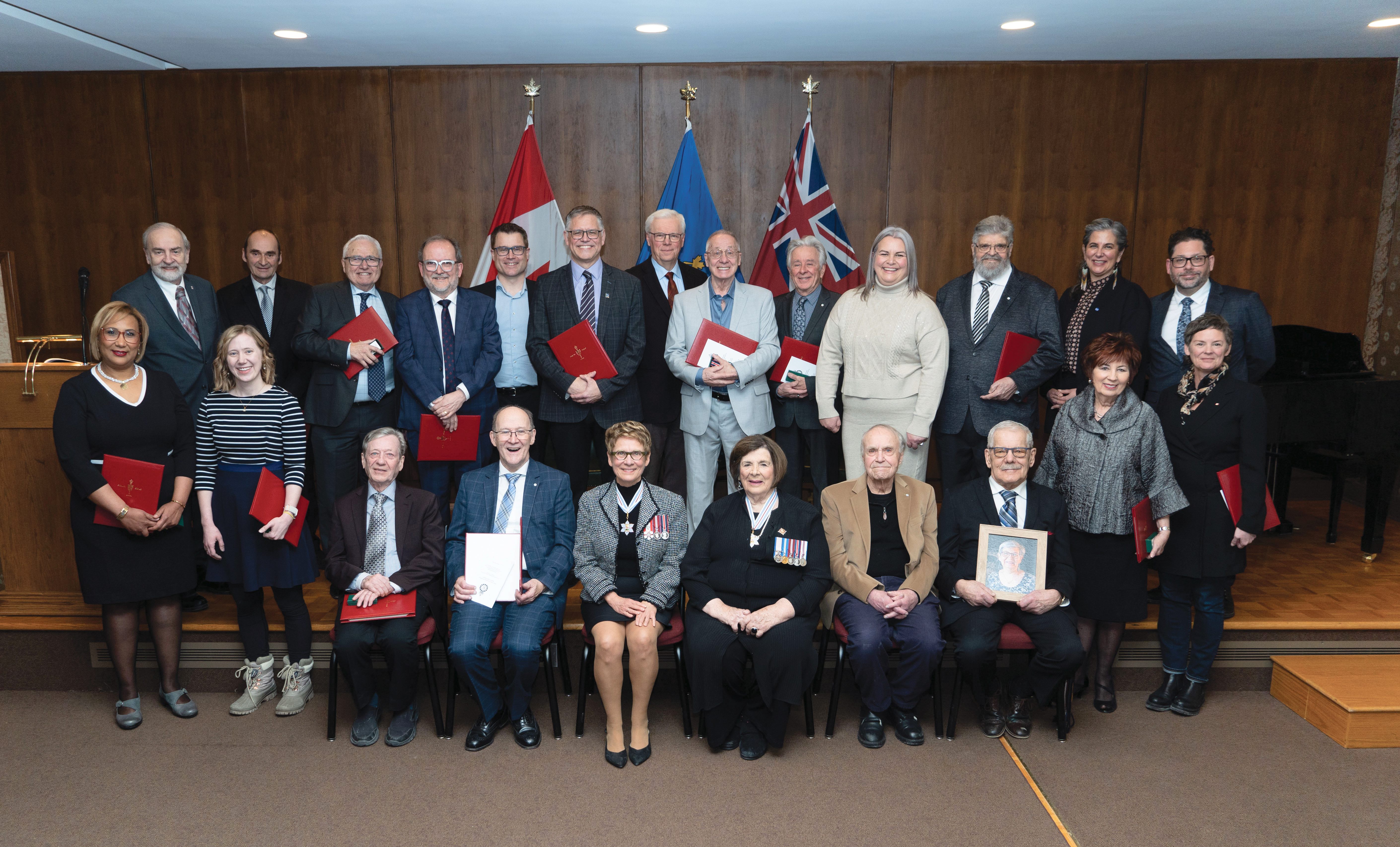 Photo de groupe avec les 21 franco-manitobains récompensés. Au premier rand au milieu, ils sont accompagnés de Raymonde Gagné, présidente du Sénat du Canada et Anita R. Neville, Lieutenante-Gouverneure du Manitoba.