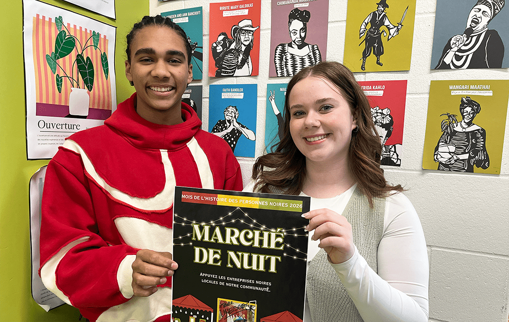Kataali Stoller et Kathryn Sacher avec une affiche pour le Marché de nuit, dans la salle de classe où se réunissent les membres du club UNESCO.