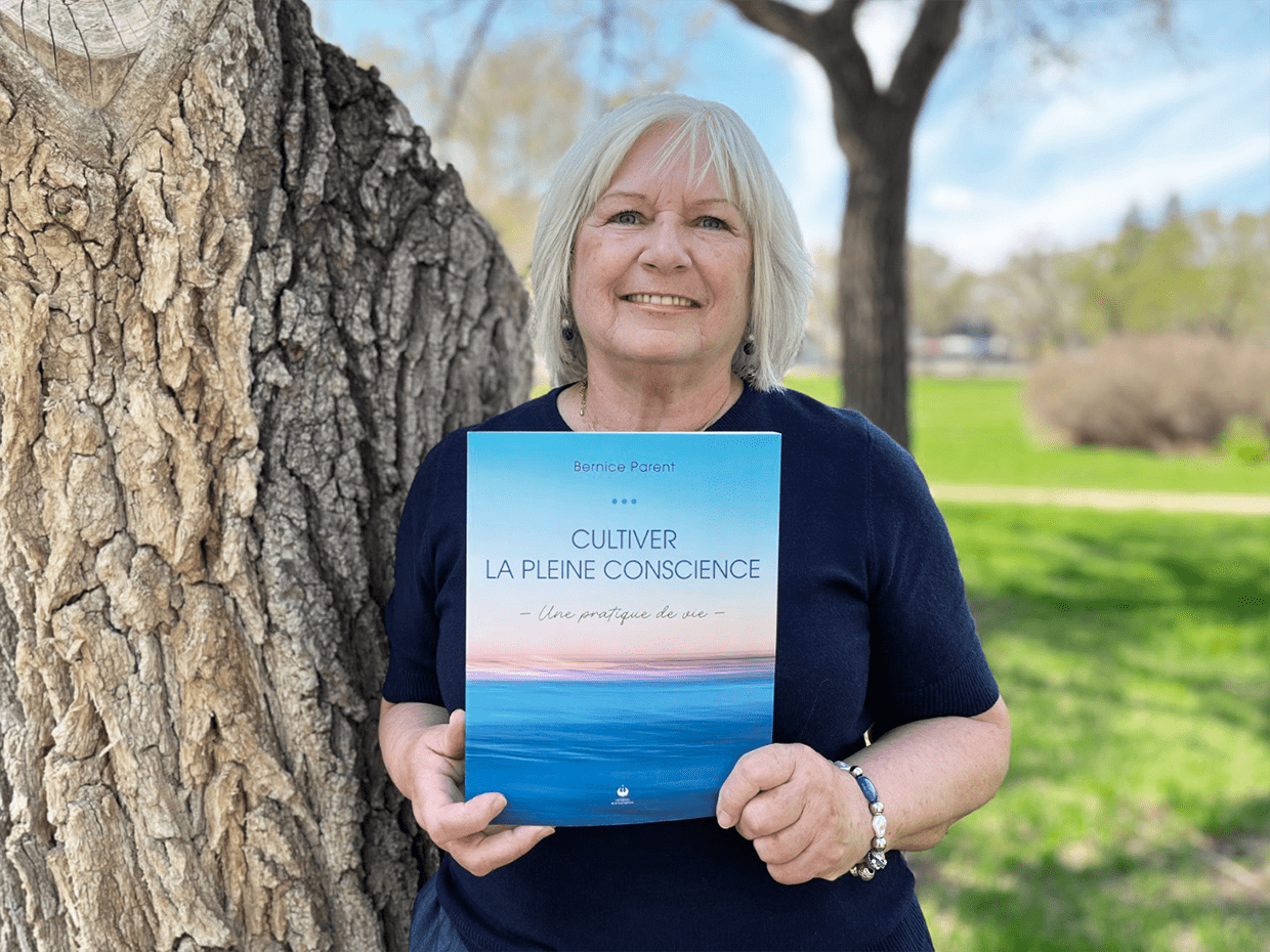 Sous le ciel bleu et au milieu des arbres du parc Coronation, Bernice Parent présente son livre.