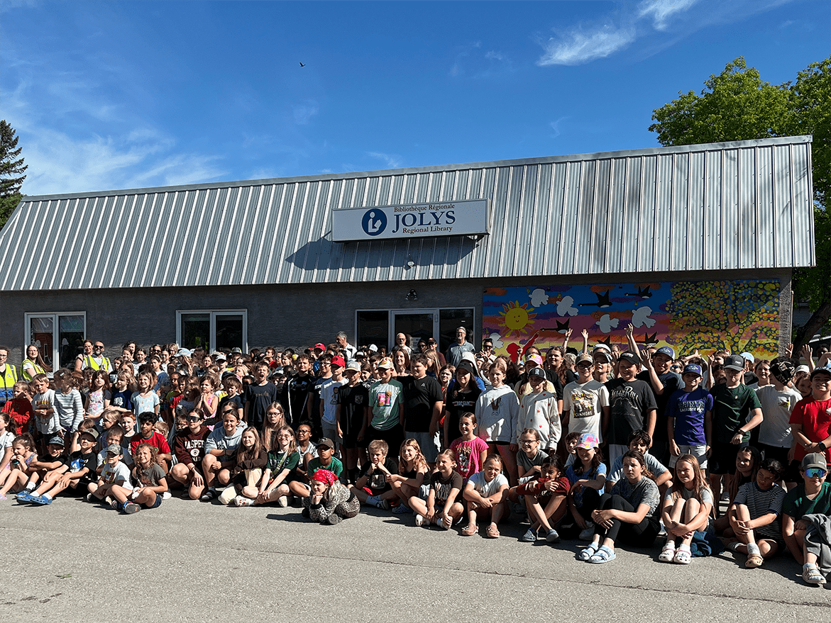 Le maire Raymond Maynard et les élèves des deux écoles devant la fresque qu’ils ont faite pour la Bibliothèque régionale Jolys.