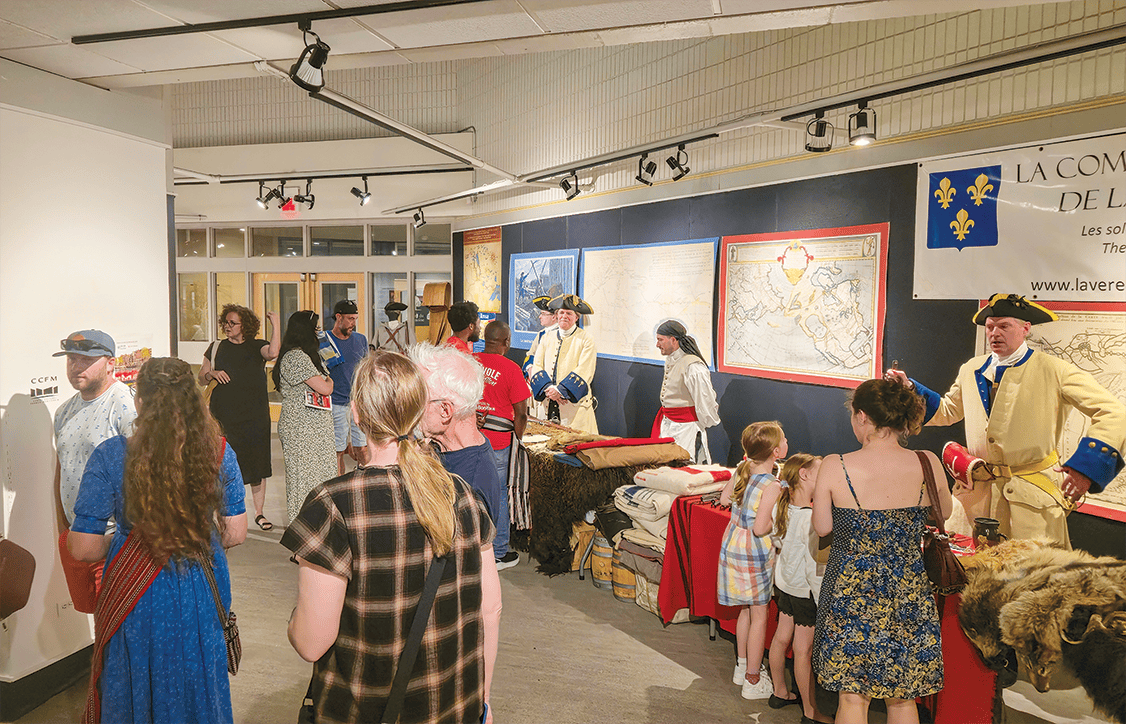 Dans la galerie d’art du CCFM, les visiteurs étaient nombreux à parcourir l’exposition culturelle du Pavillon canadien-français, où costumes, objets et cartes d’époque leur faisaient découvrir le folklore et le patrimoine de la communauté.